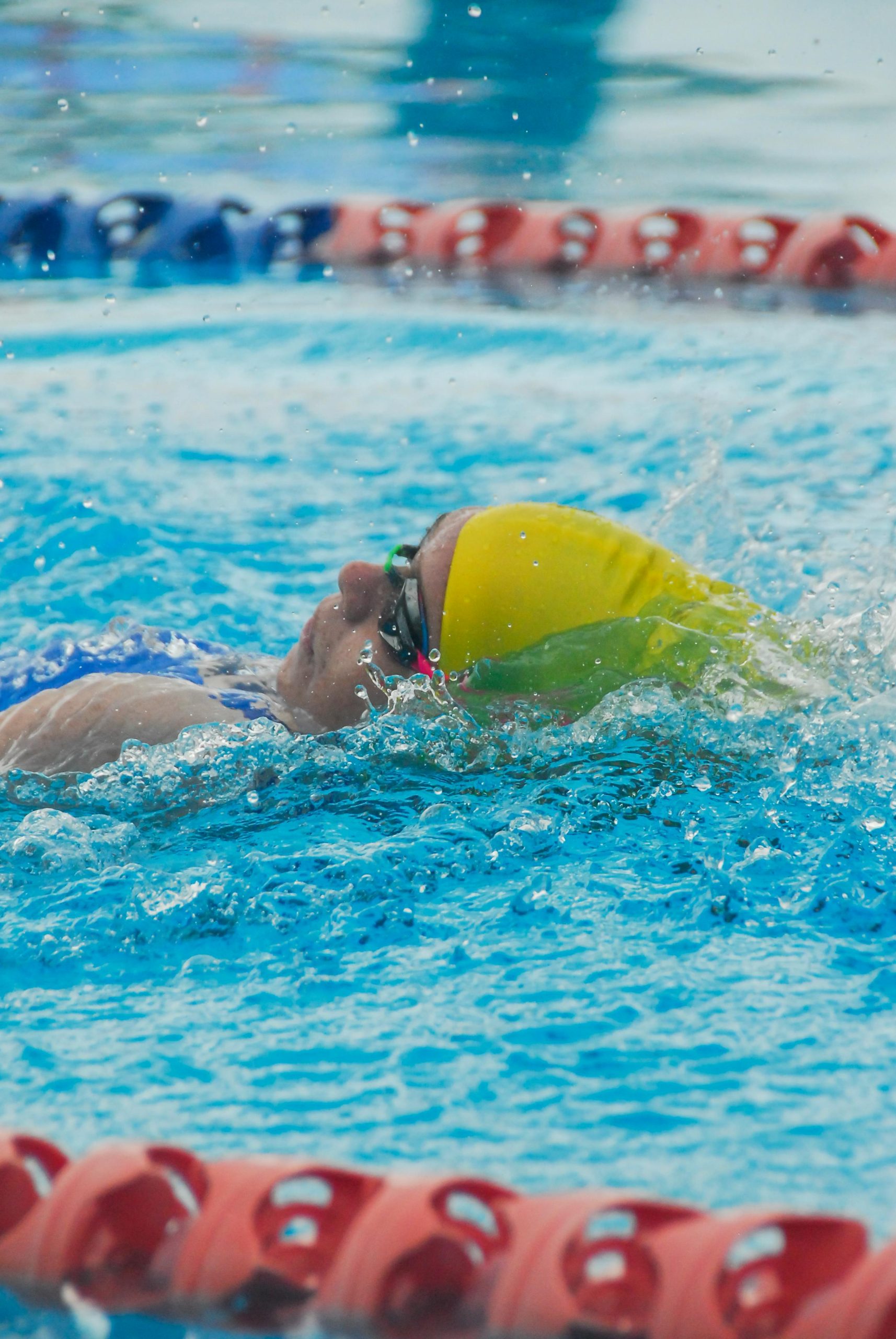 Swimmer with colorful cap in a bright blue pool, showcasing athletic energy.